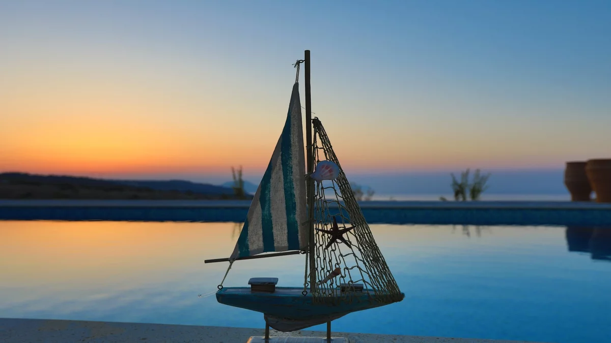 Kleines Segelboot vor Pool bei Sonnenuntergang