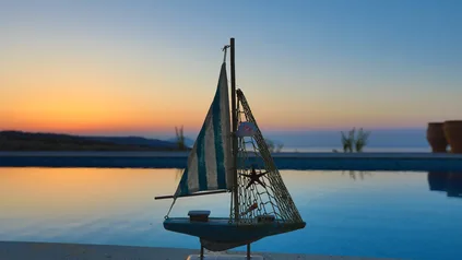 A small sailing boat by the pool at sunset